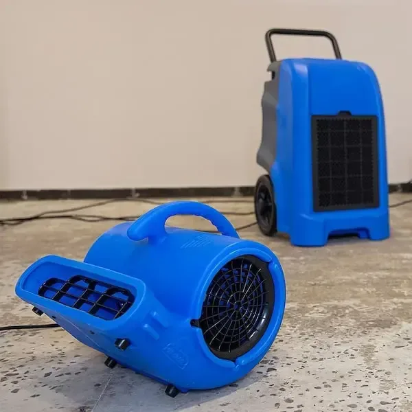 Blue air mover and dehumidifier on a stripped concrete floor